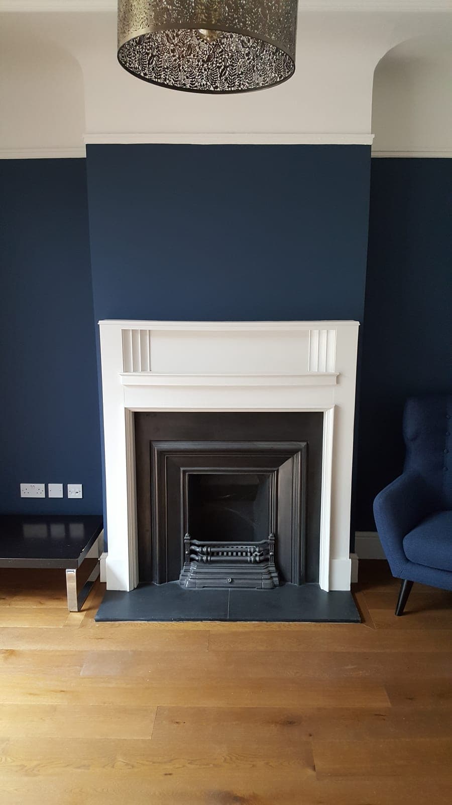Period-style fireplace against a navy feature wall