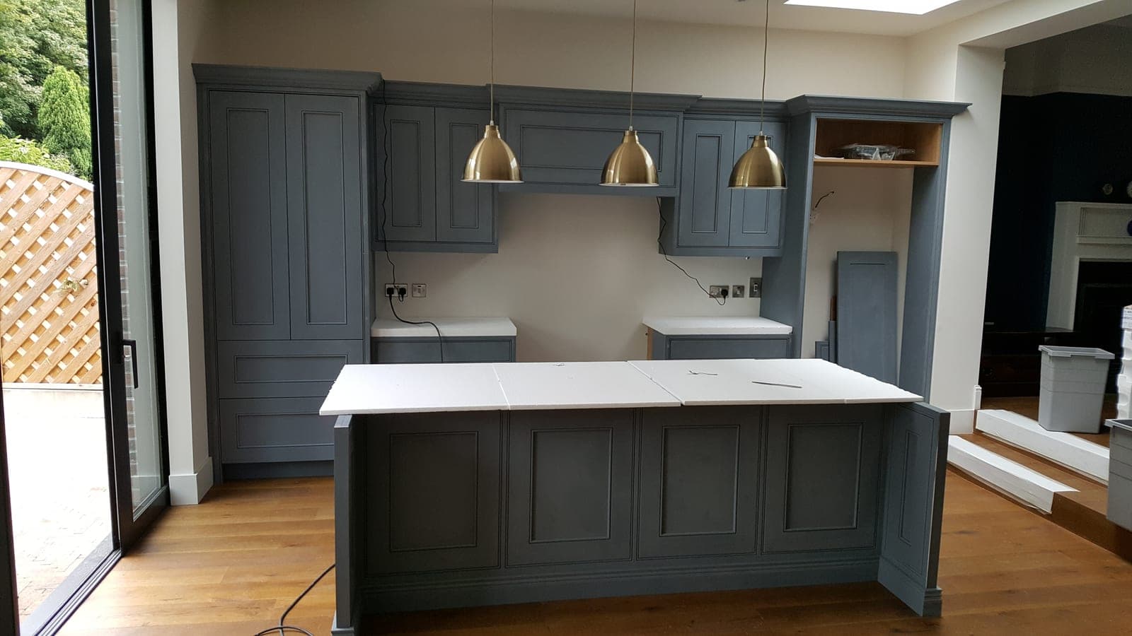 Navy Shaker kitchen with brass pendants and a white-topped island
