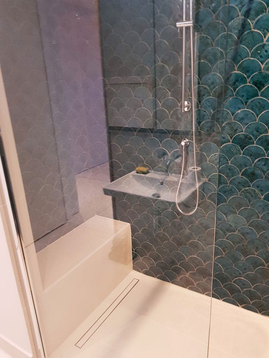 Walk-in shower finished in green fish-scale tiles