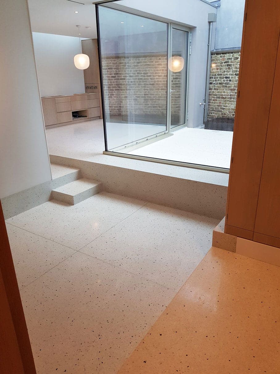 Terrazzo floor stepping up to a glazed courtyard room