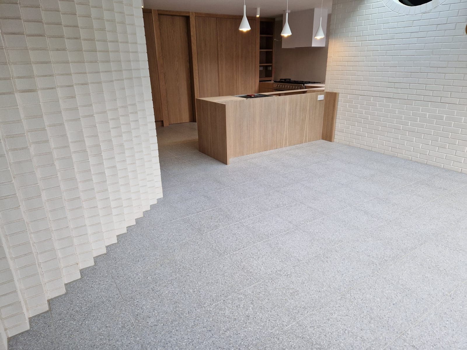 Textured white brick feature wall beside an oak kitchen island