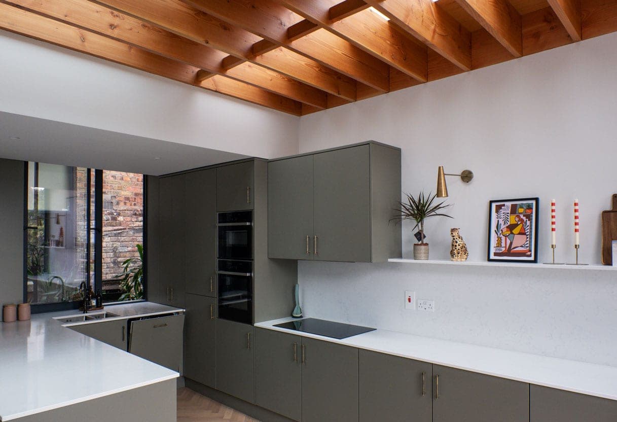 Sage green kitchen with a white stone worktop