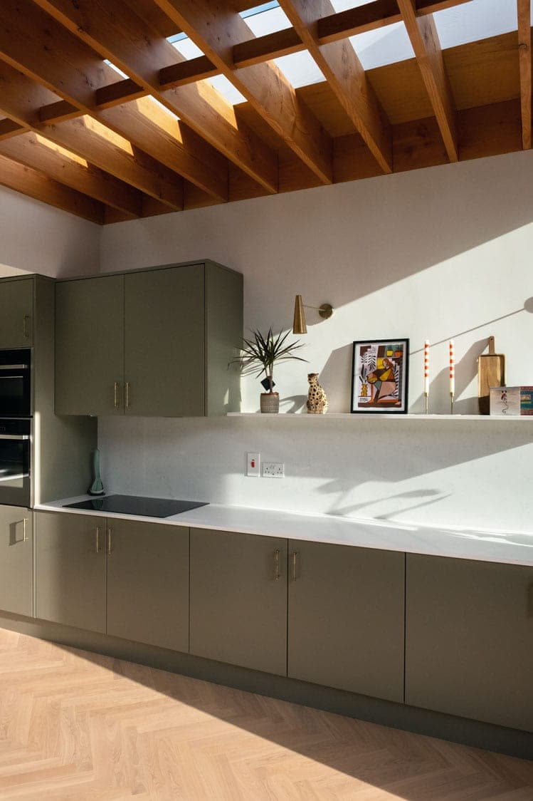 Sage green kitchen run with open shelving and exposed joists